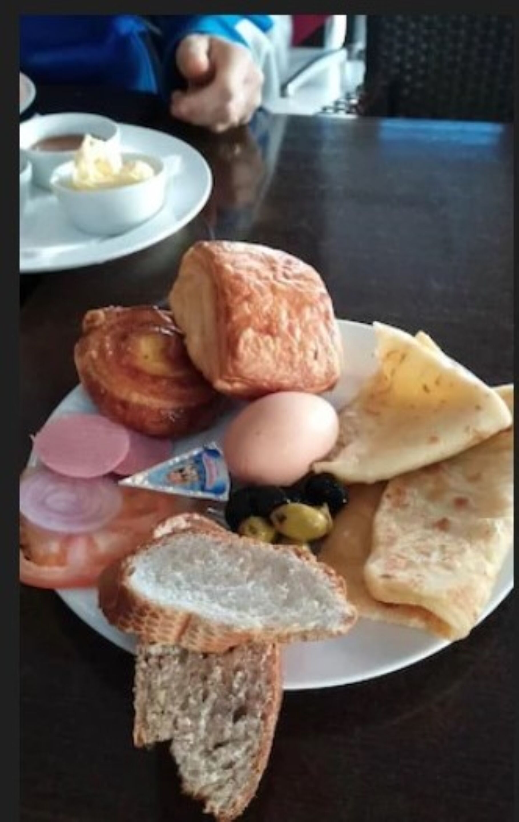 A plate with various food items including bread, a pastry, an egg, and some vegetables.