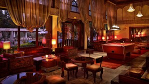 A dimly lit lounge area with a pool table, comfortable seating, and large windows with curtains. - El Andalous Lounge & Spa Hotel (Marrakech)