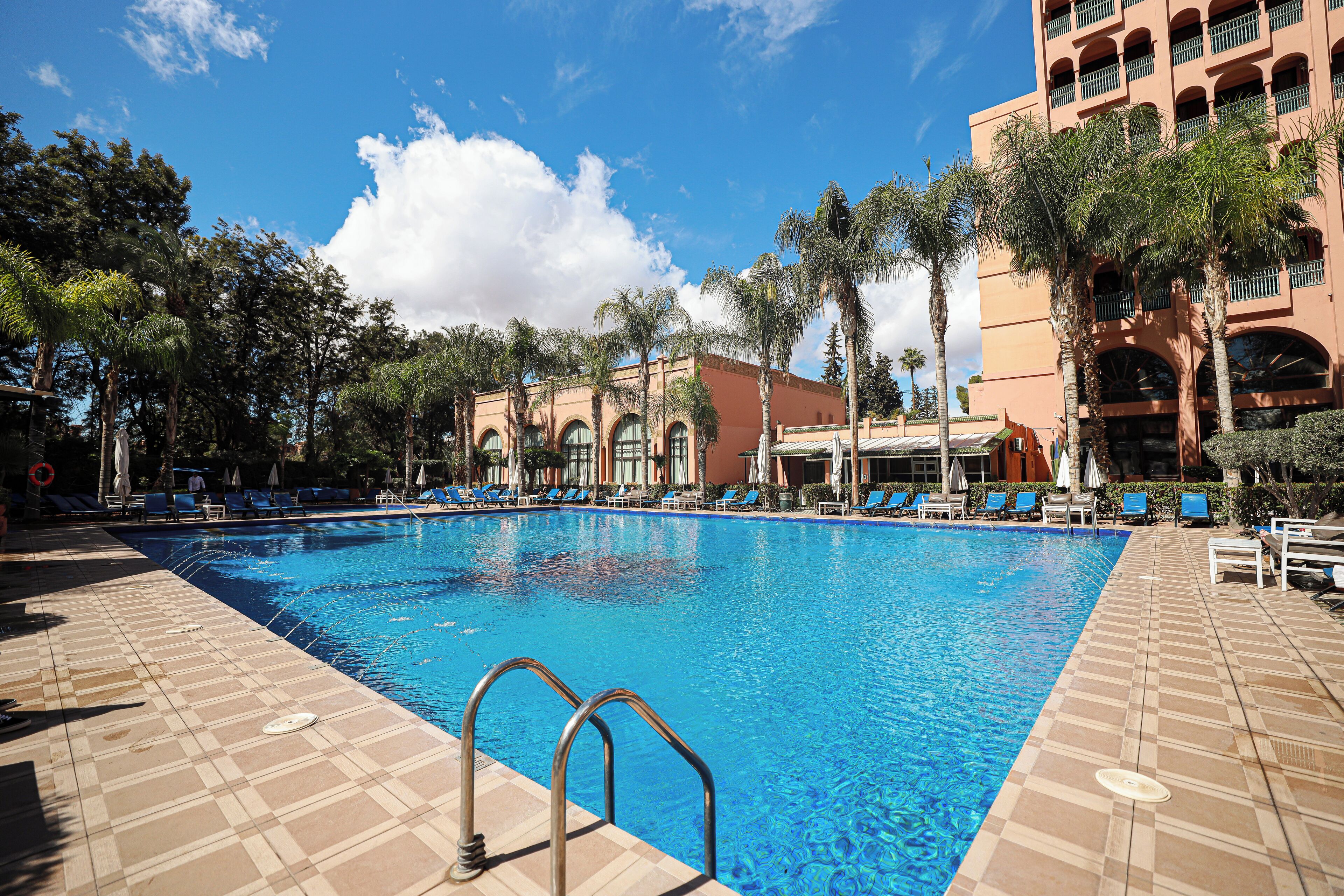 Una piscina al aire libre, sombrillas, tumbonas