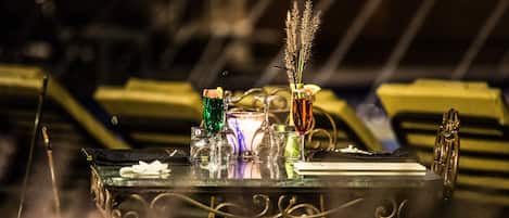 A table with various glassware and a candle, set against a blurred background.