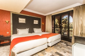 Habitación de hotel con una cama grande, dos mesitas de noche, una lámpara de noche, una ventana con cortinas y vistas al exterior.