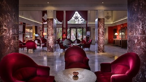 A lobby with red upholstered chairs, marble columns, and a chandelier. - El Andalous Lounge & Spa Hotel (Marrakech)