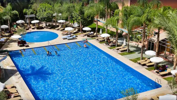 A large rectangular pool with multiple lanes, surrounded by palm trees and sun loungers. - El Andalous Lounge & Spa Hotel (Marrakech)