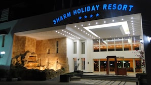 The exterior of the Sharm Holiday Resort with a large illuminated sign, a stone facade, and a modern entrance. - Sharm Holiday Resort (Sharm El Sheikh)