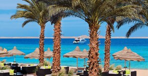 A beachside resort with palm trees, thatched umbrellas, and lounge chairs. - Baron Resort Sharm El Sheikh (Sharm El Sheikh)
