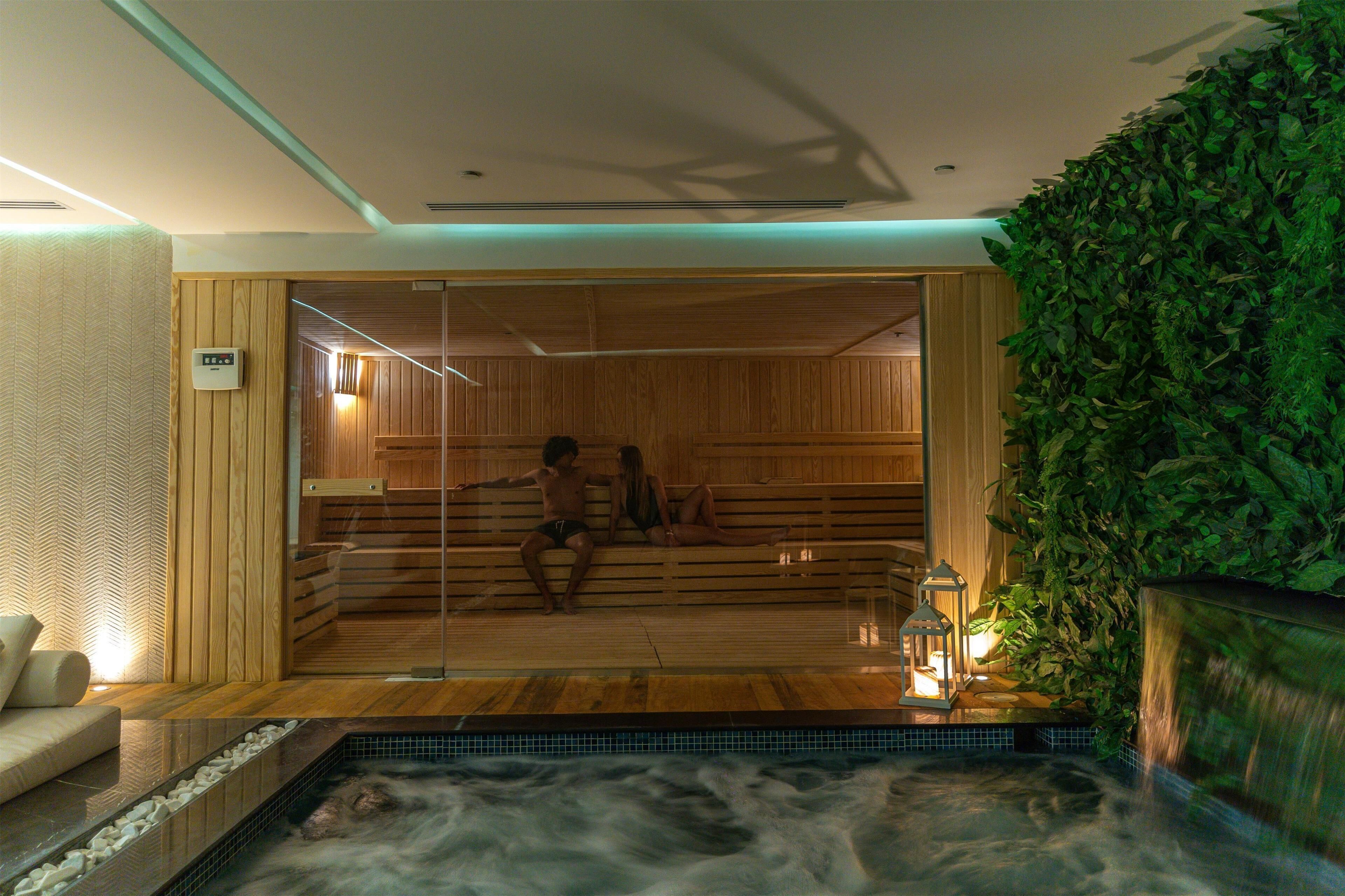 Eine Sauna mit Holzbänken, einem kleinen Pool und einer grünen Wand.