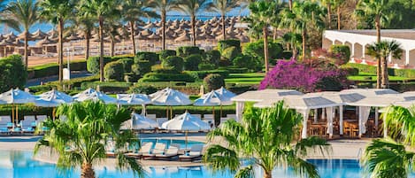 Un resort con piscina, sillas de descanso, sombrillas y vista al mar.