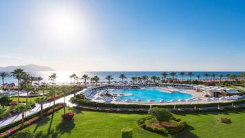 Ein Resort mit einem großen, runden Pool, Palmen und Blick auf den Ozean.