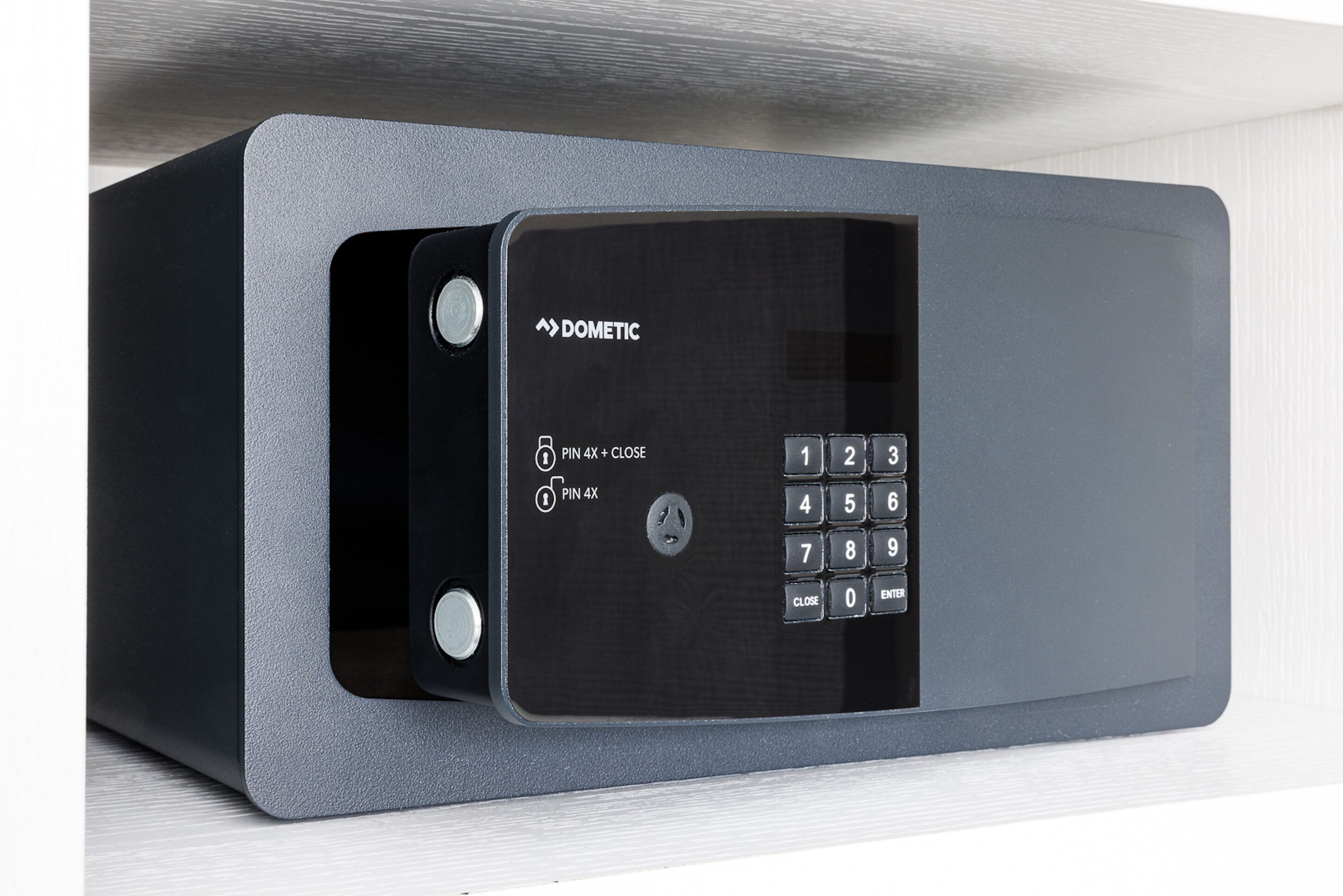 Objecte negre, rectangular i metàl·lic amb un teclat i un botó circular, amb la marca "DOMETIC".