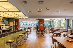 A spacious restaurant with a long counter, multiple seating areas, and a tropical mural on the wall.