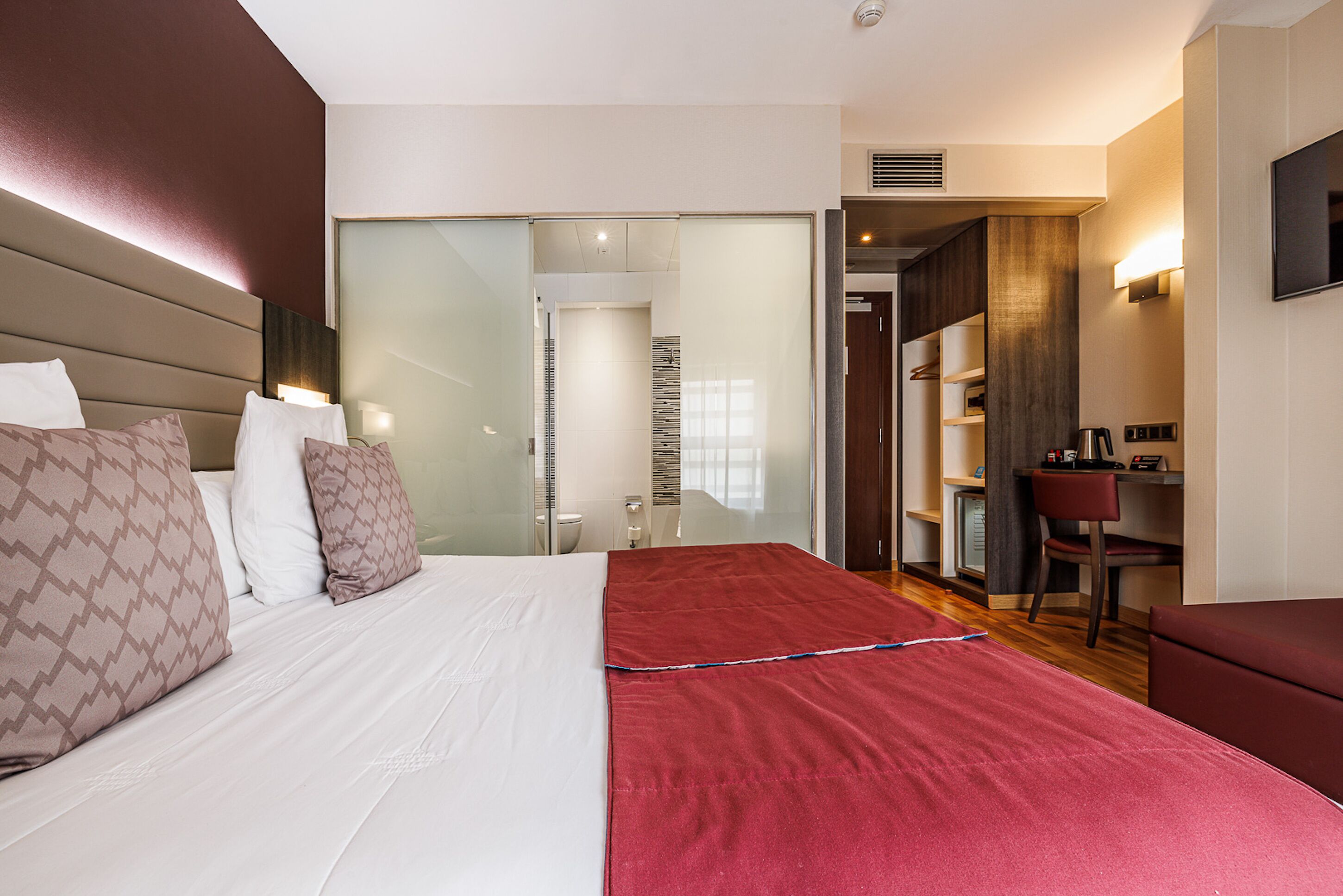 Quarto de hotel moderno com uma cama grande, uma escrivaninha e um guarda-roupa.