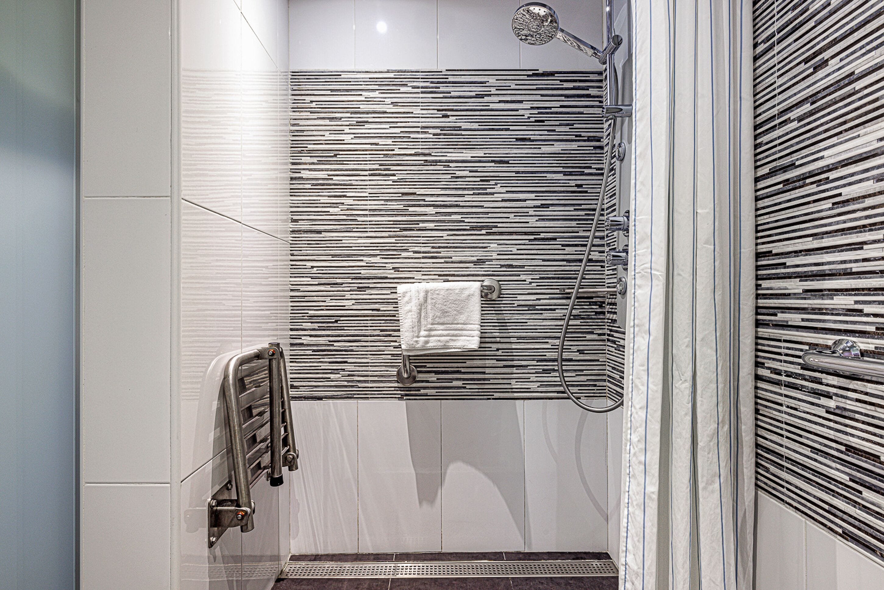 Une salle de bain moderne équipée d’une douche, d’un porte-serviettes et d’un radiateur en métal.