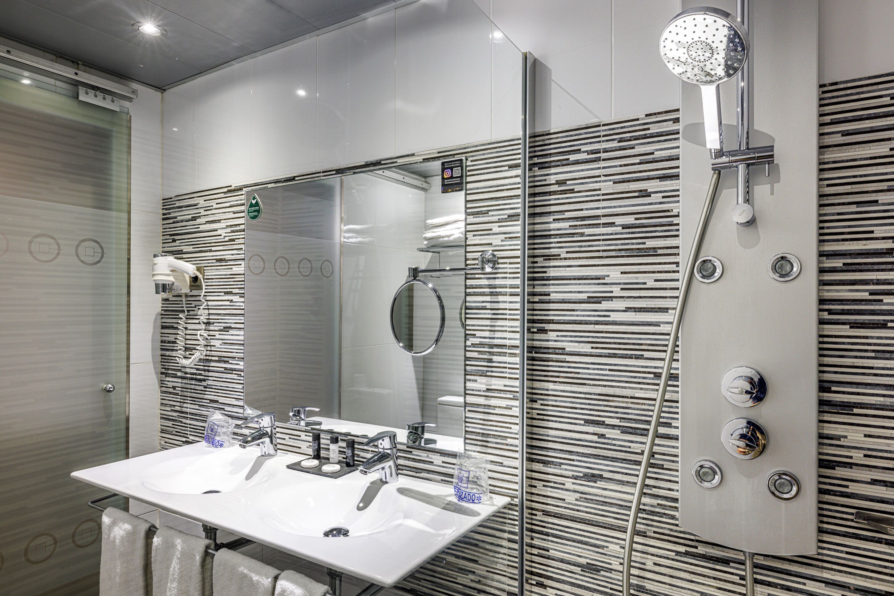 Un baño moderno con un espejo grande, dos lavabos y una ducha.