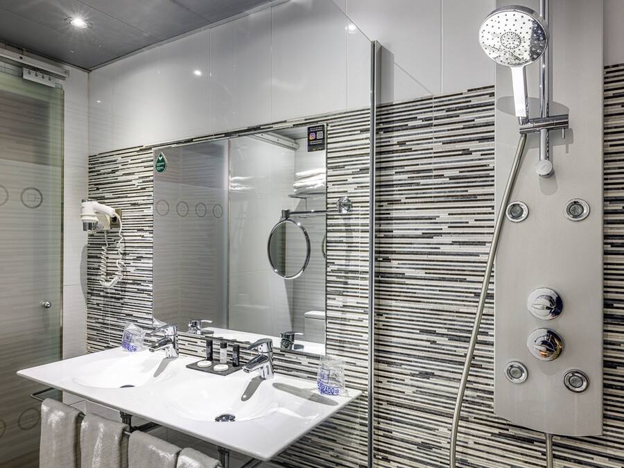 Un baño moderno con un espejo grande, dos lavabos y una ducha.