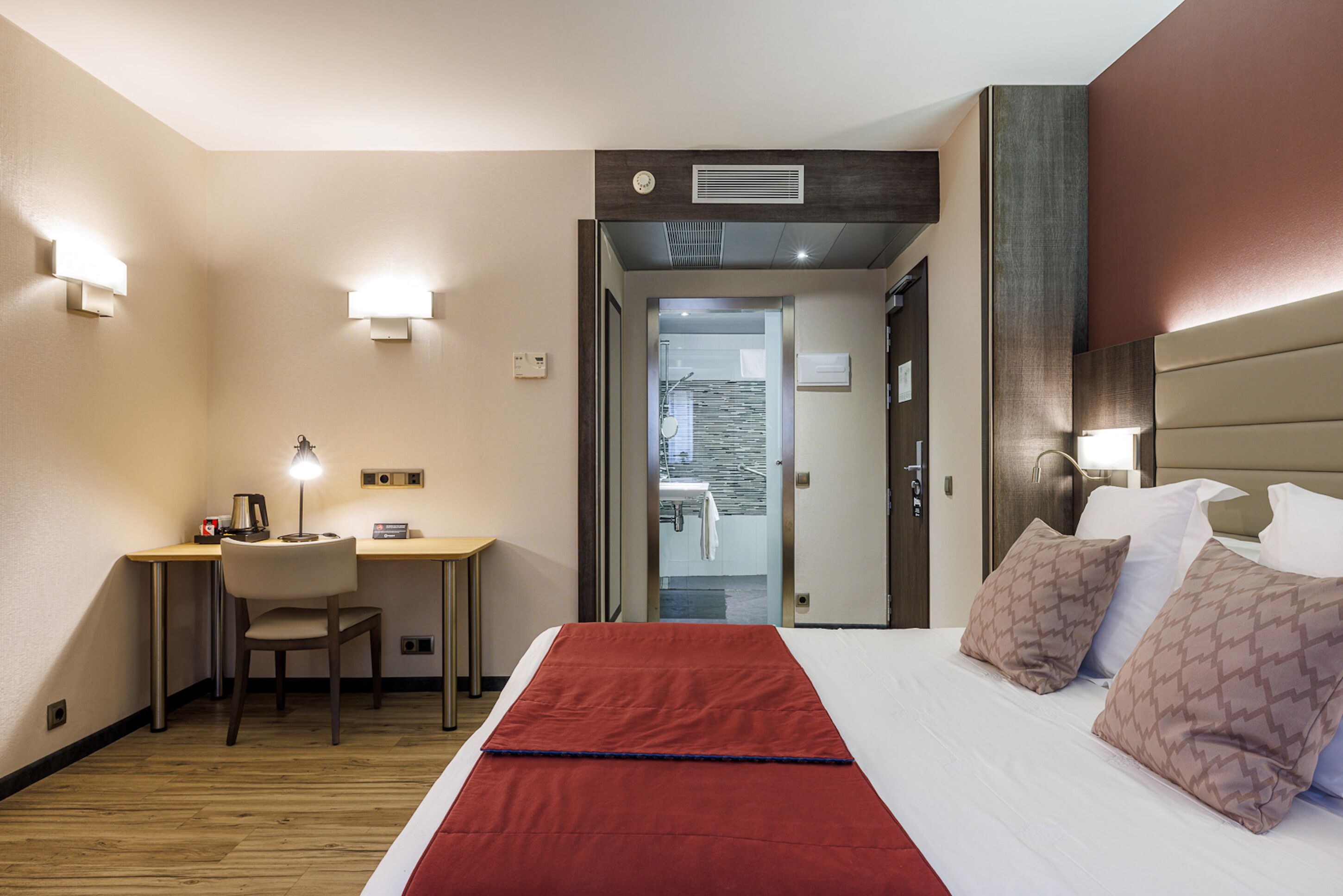 A hotel room with a bed, a desk, and a chair.