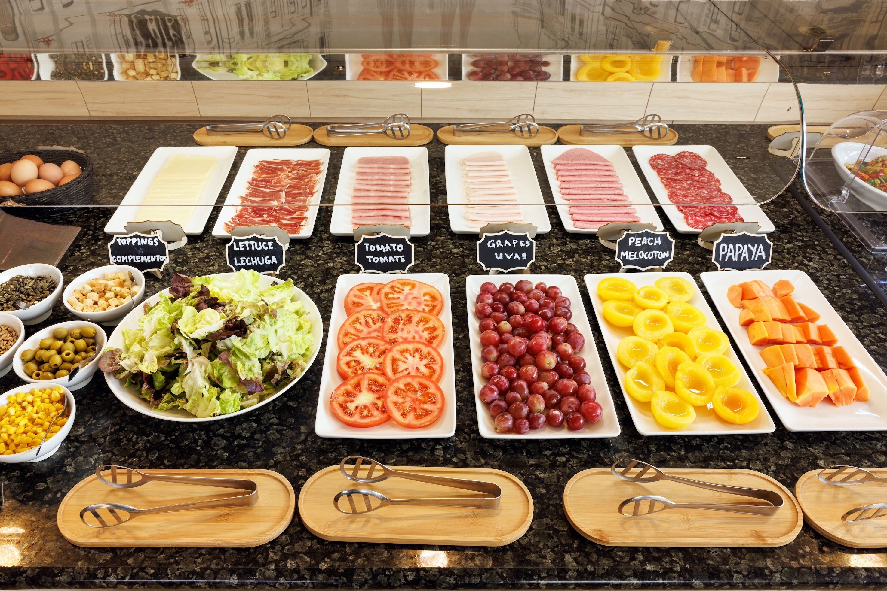 Un bufé con diversas opciones de comida, incluyendo carnes, quesos y frutas.