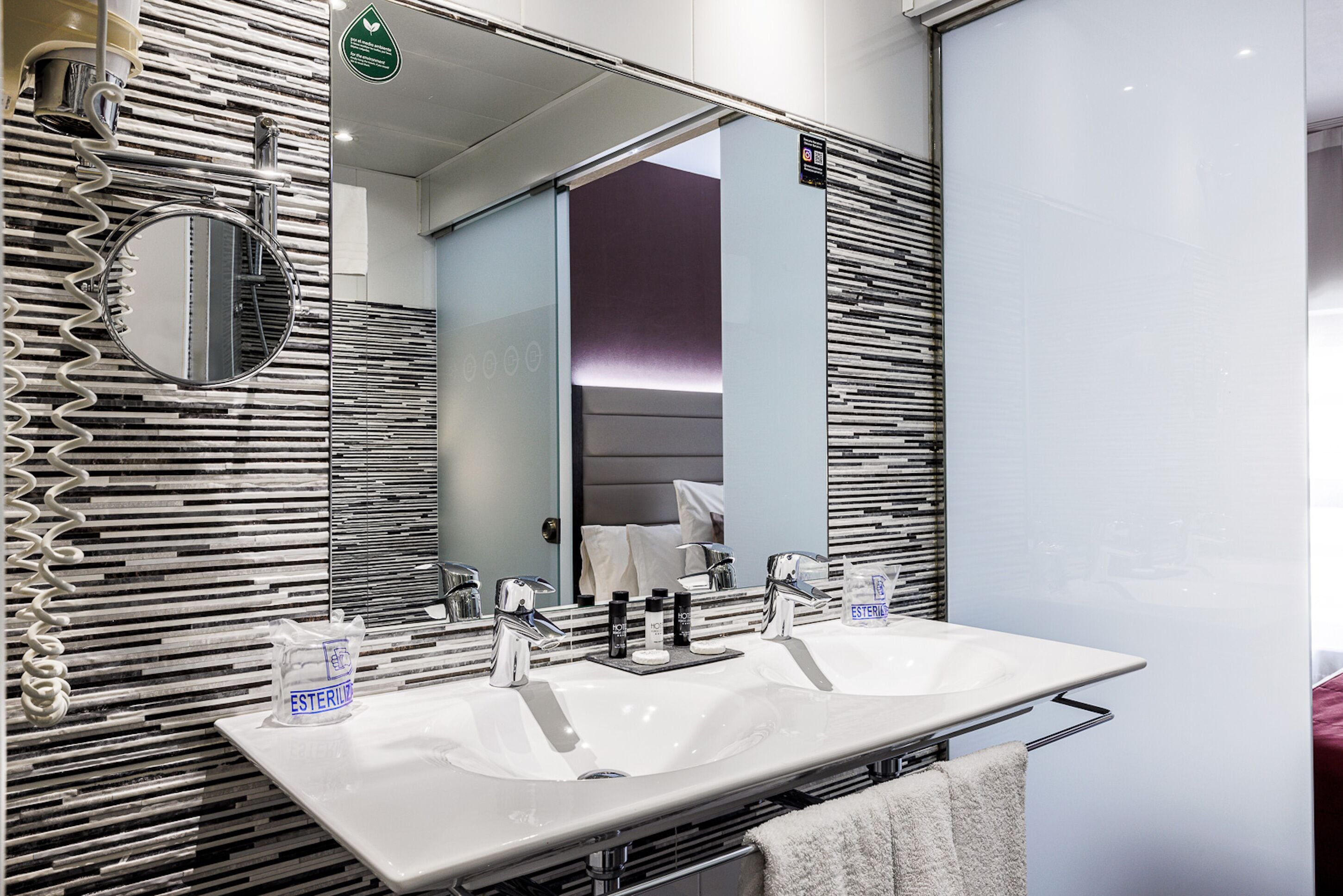 Un baño moderno con dos lavamanos, un espejo grande y un perchero para toallas.