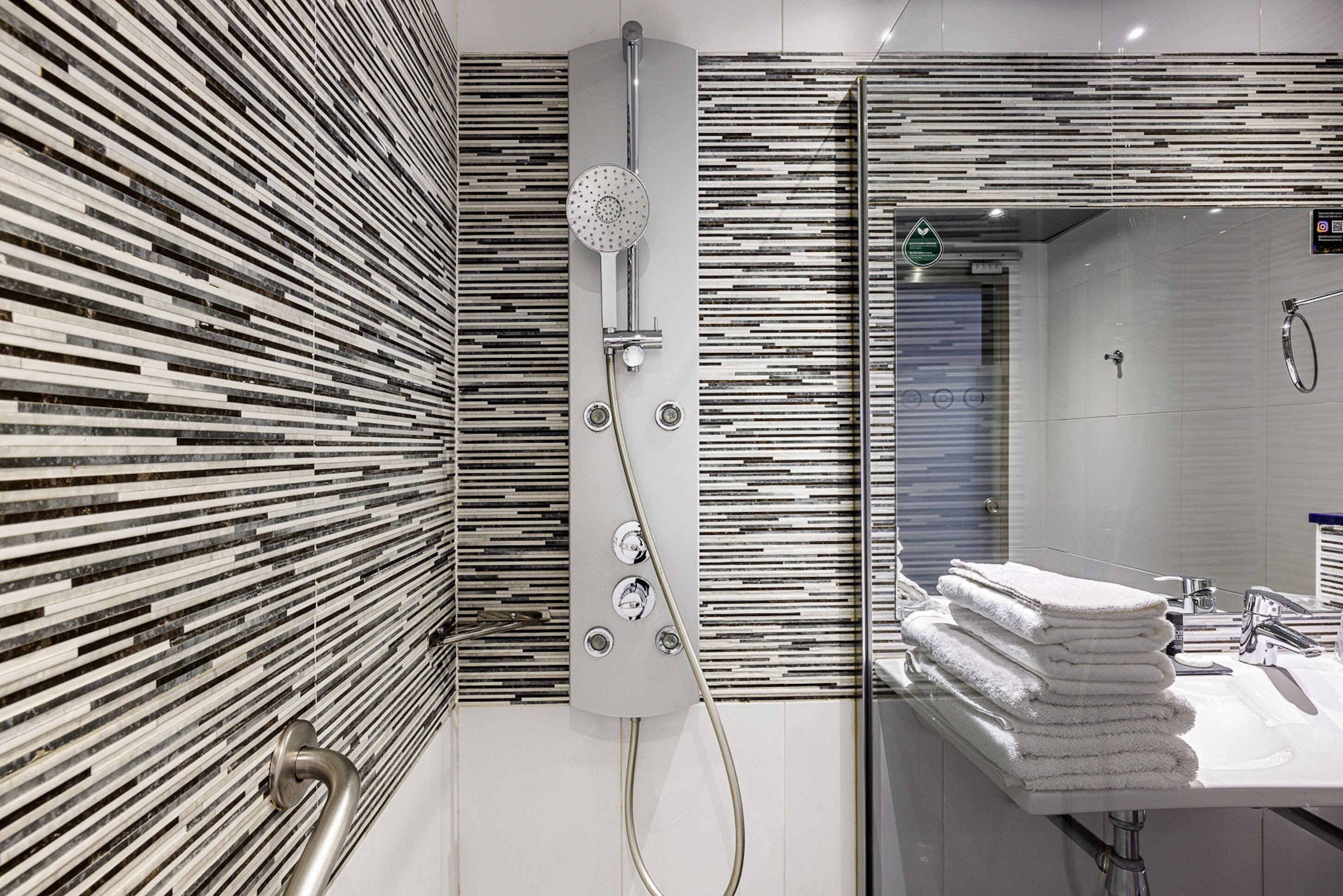 Un baño moderno con ducha, lavamanos y espejo.