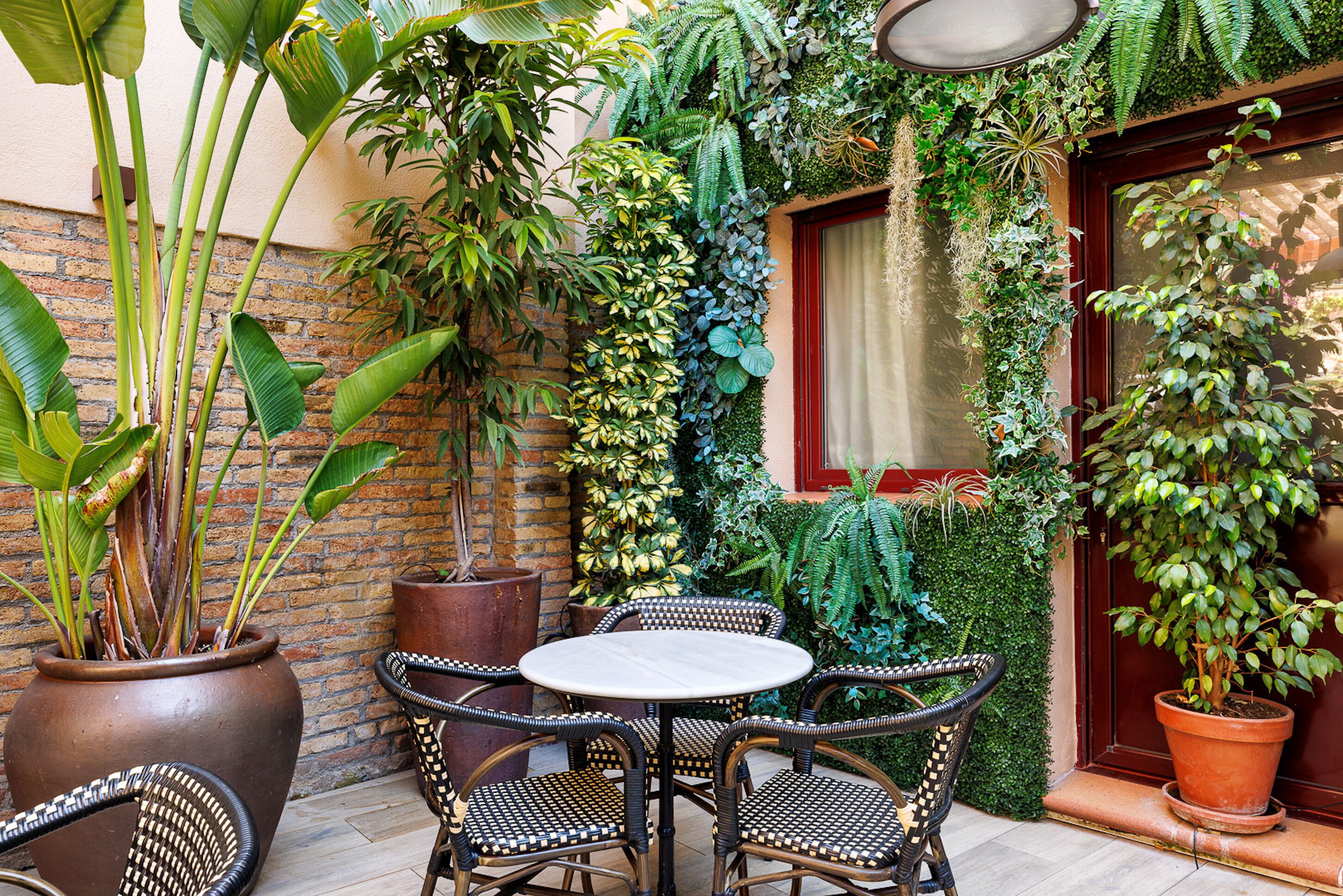 Un patio con sillas de mimbre, una mesa redonda y plantas en macetas.