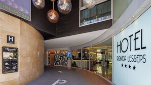A hotel entrance with a clear path marked by a 'P' for parking, a reception area with a glass facade, and a sign indicating the hotel name 'HOTEL RONDA LESSEPS'. - Hotel Ronda Lesseps (Barcelona)