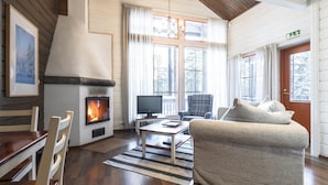 Un salón acogedor con chimenea, muebles de madera y ventanas amplias.