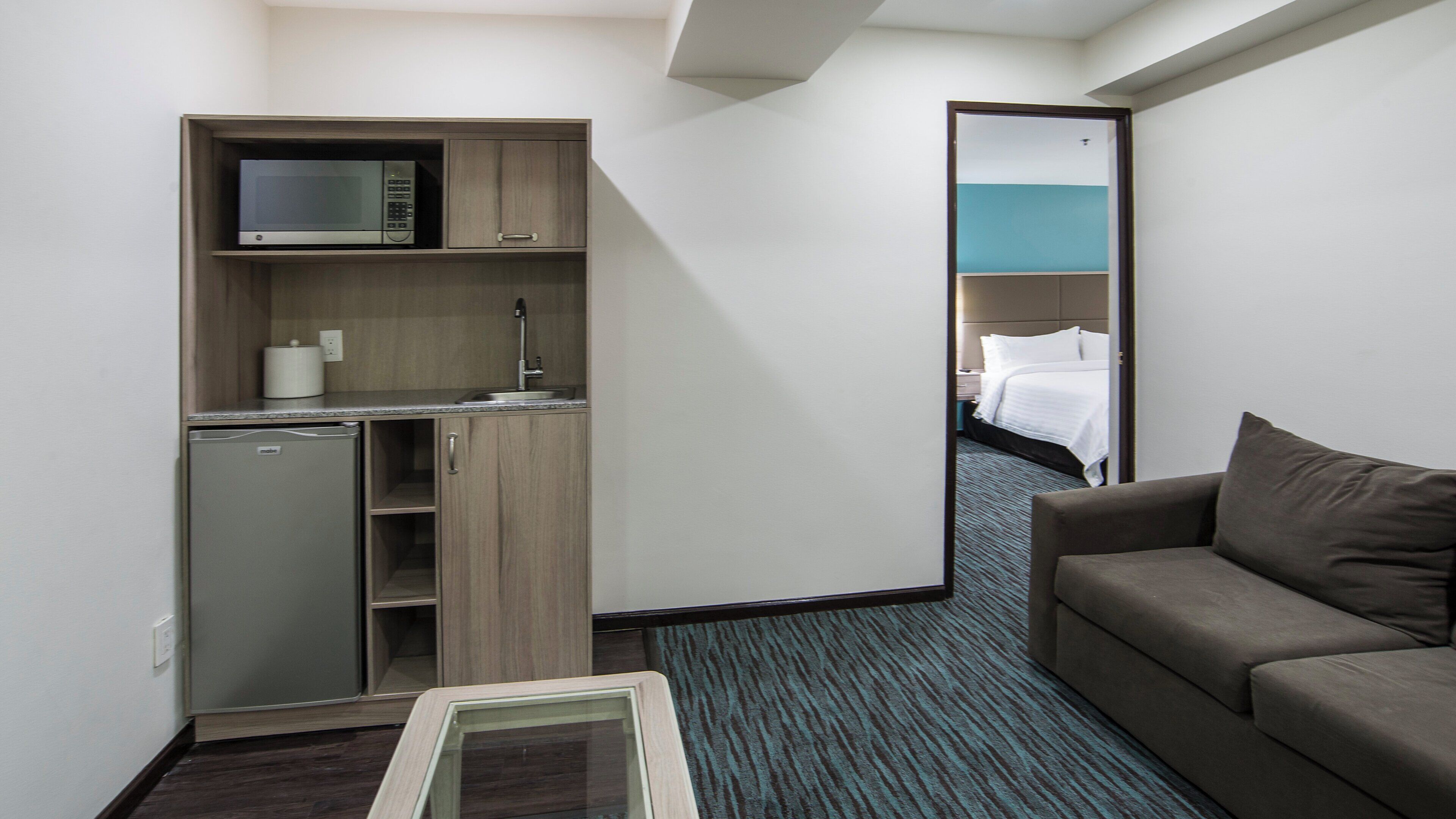 Une chambre d’hôtel compacte comprenant un coin cuisine, un lit et un canapé.