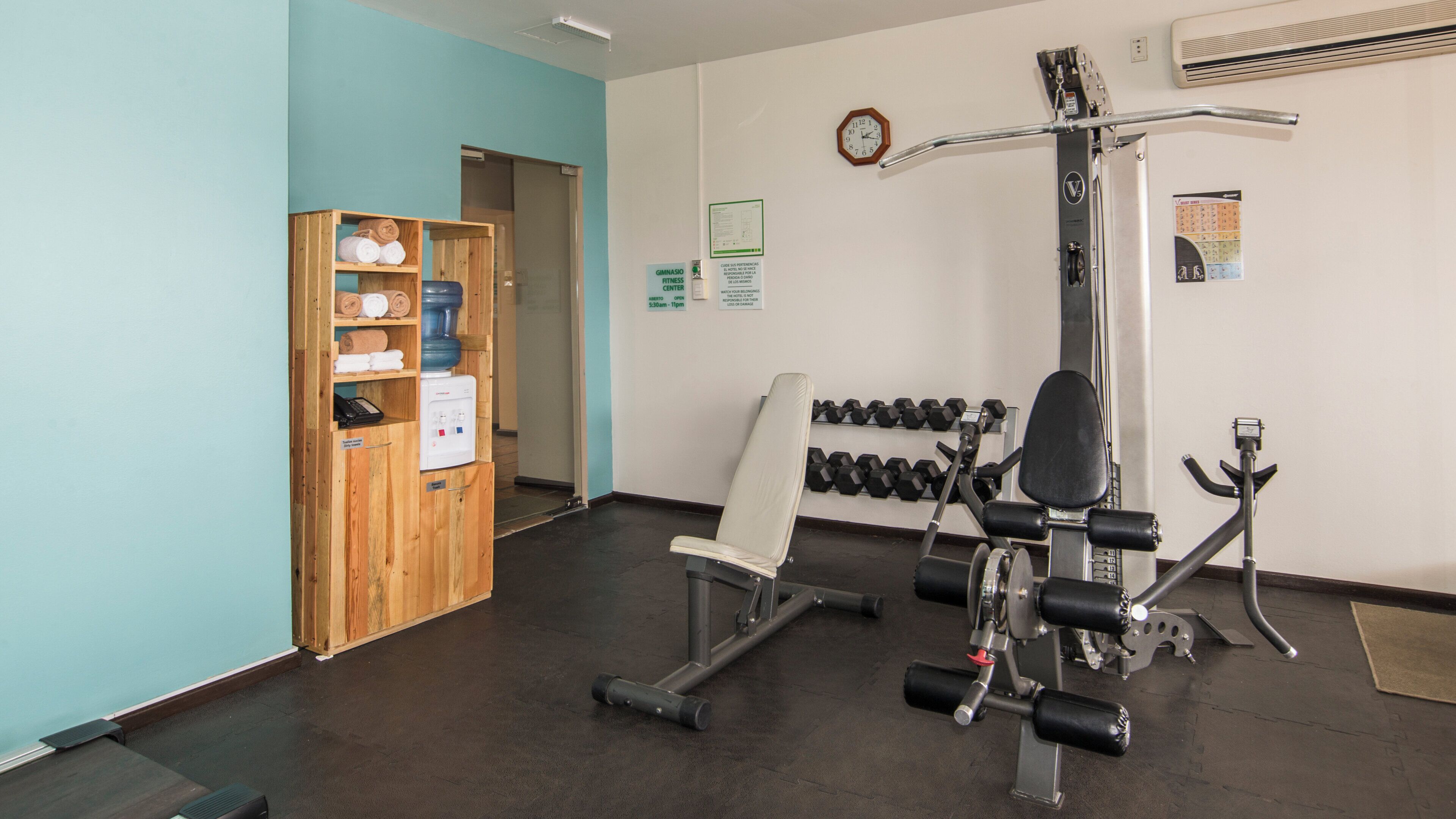 A gym with weightlifting equipment, a bench, and a water dispenser.