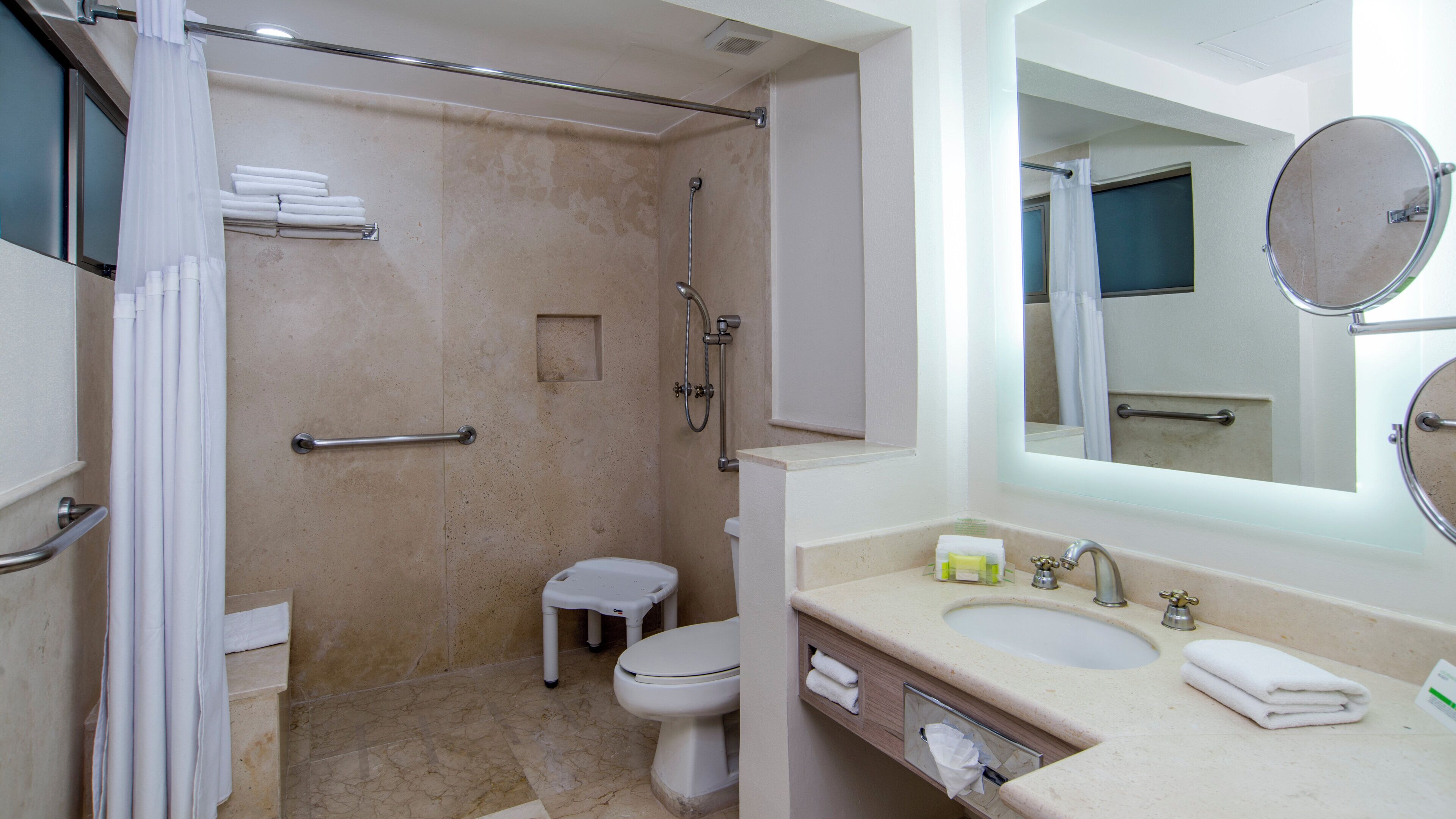 Une salle de bain équipée d’une douche, de toilettes, d’un lavabo et d’un miroir.