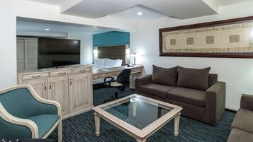 A hotel room with a bed, desk, television, and seating area.