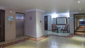 A hotel lobby with elevators, a reception desk, and seating area.