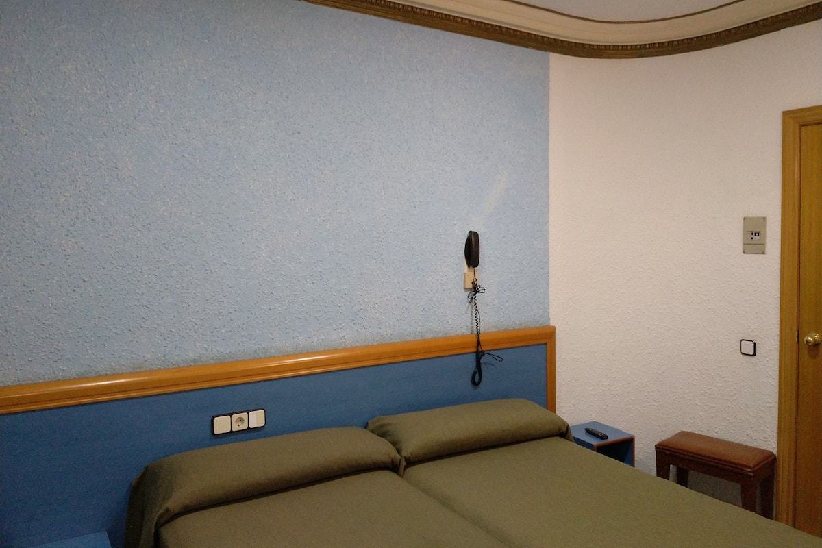 Ein Hotelzimmer mit Bett, Nachttisch, Telefon und Tür.