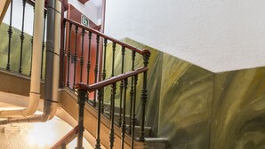 A staircase with a handrail, steps, and a wall with a greenish pattern.