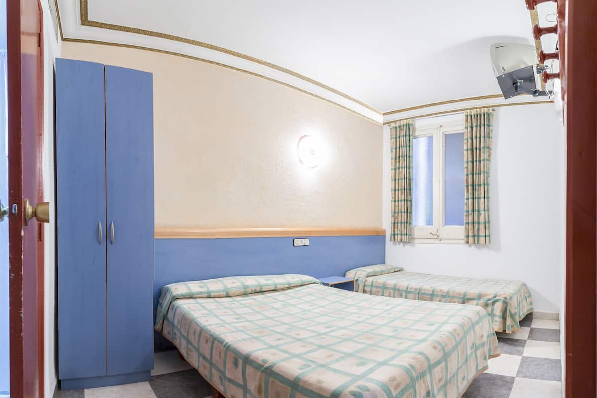 Ein Zimmer mit zwei Betten, einem Schrank, einem Fenster mit Vorhängen und einer Deckenleuchte.