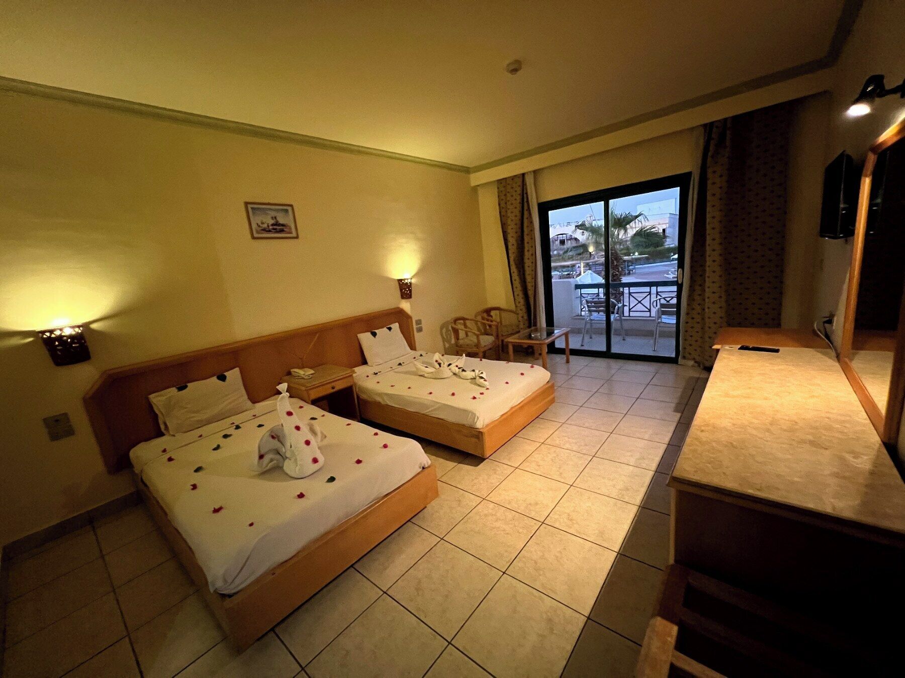 Une chambre d’hôtel avec deux lits, un balcon et un bureau.