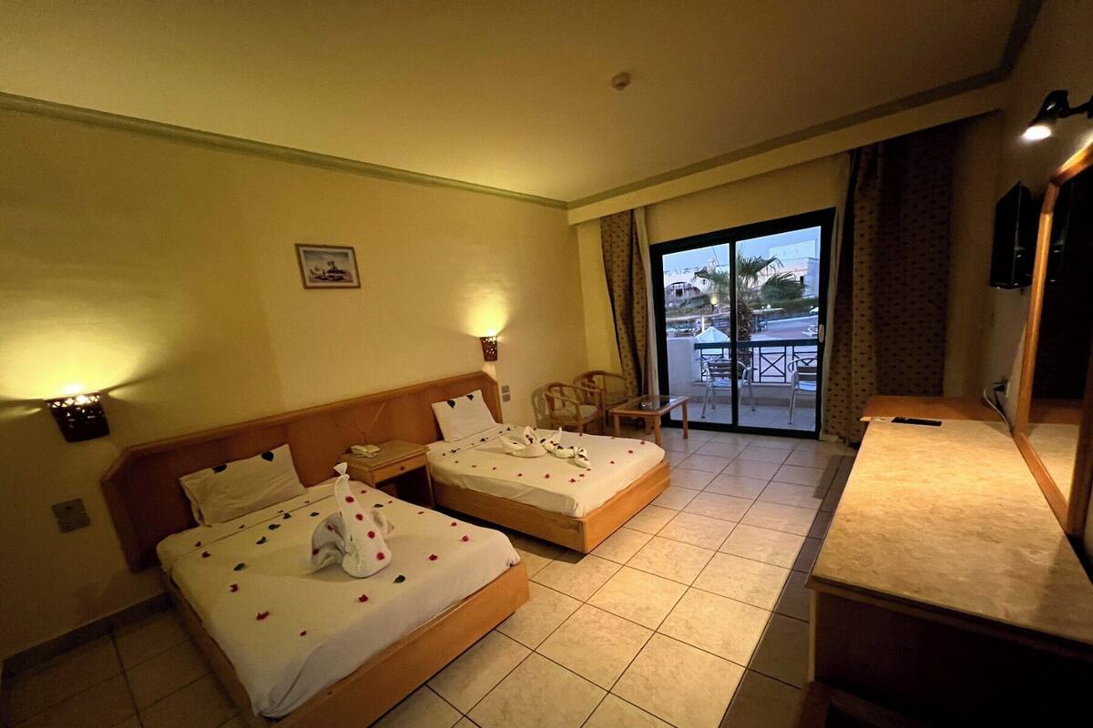 Una habitación de hotel con dos camas, un balcón y un escritorio.