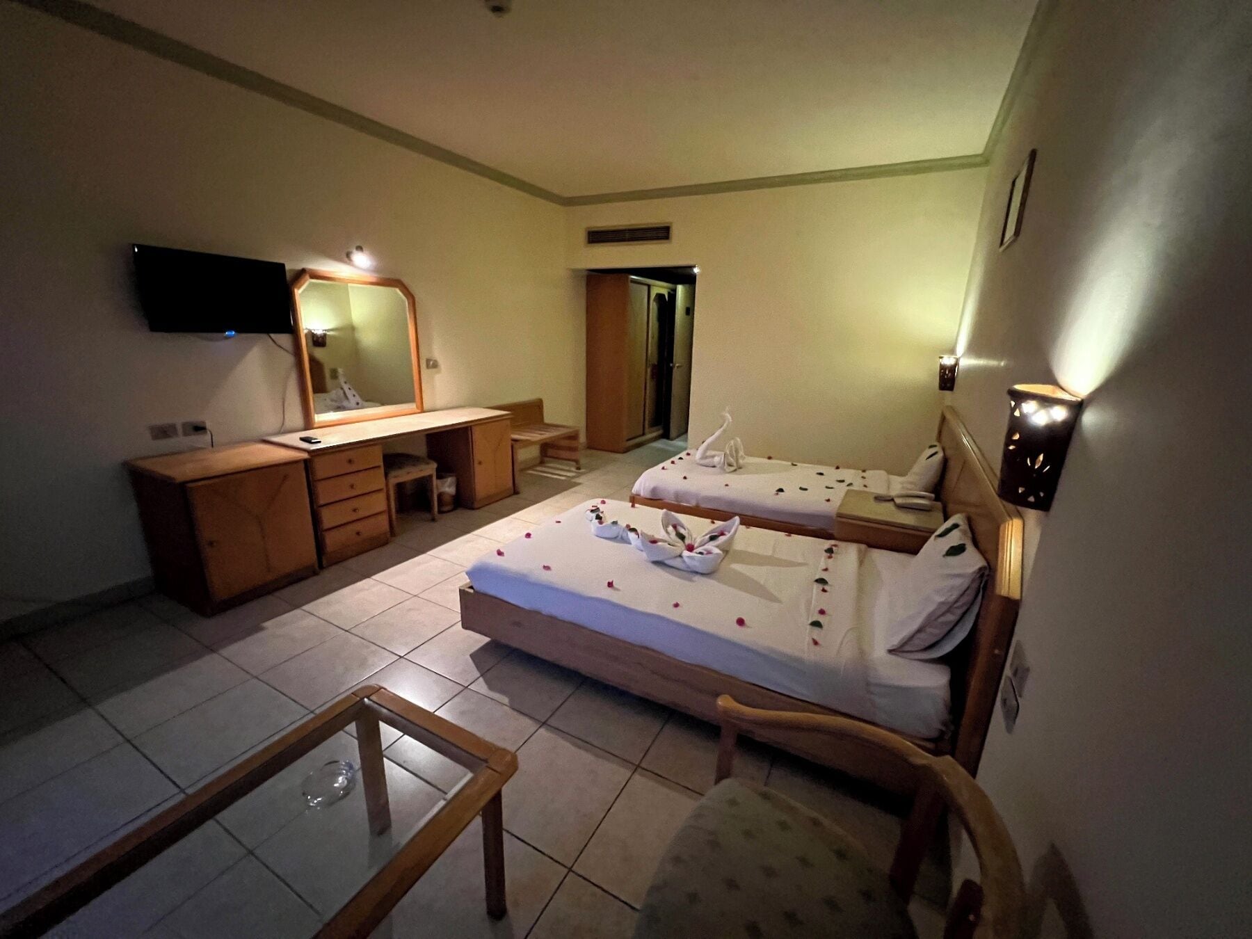 Une chambre d’hôtel avec deux lits, un bureau, une chaise, une télévision et un miroir.