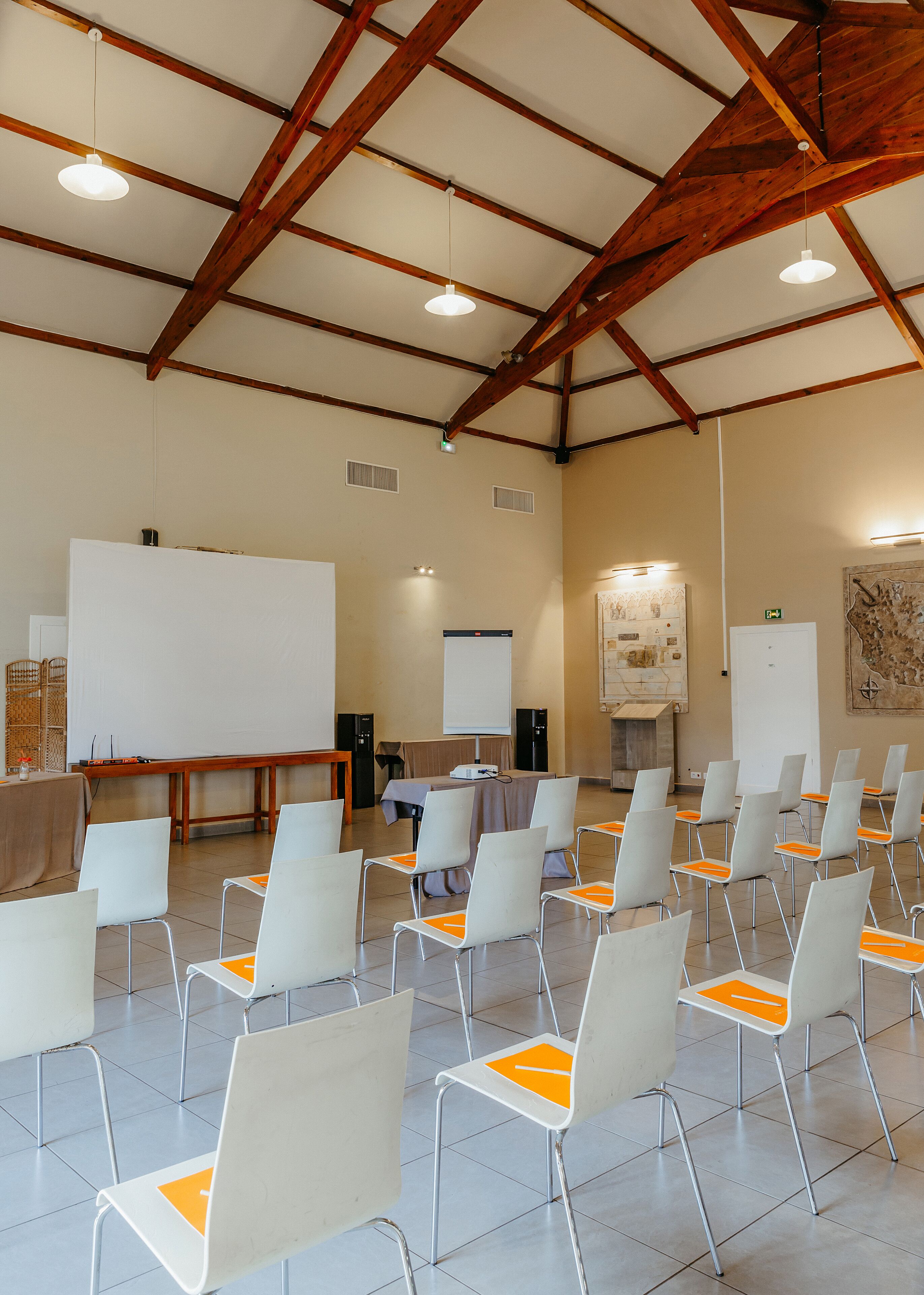 A conference room with white chairs, a whiteboard, a projector, and a wooden ceiling.