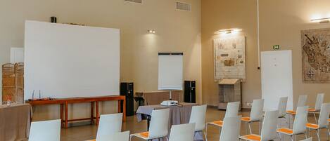 A conference room with white chairs, a whiteboard, a projector, and a wooden ceiling.