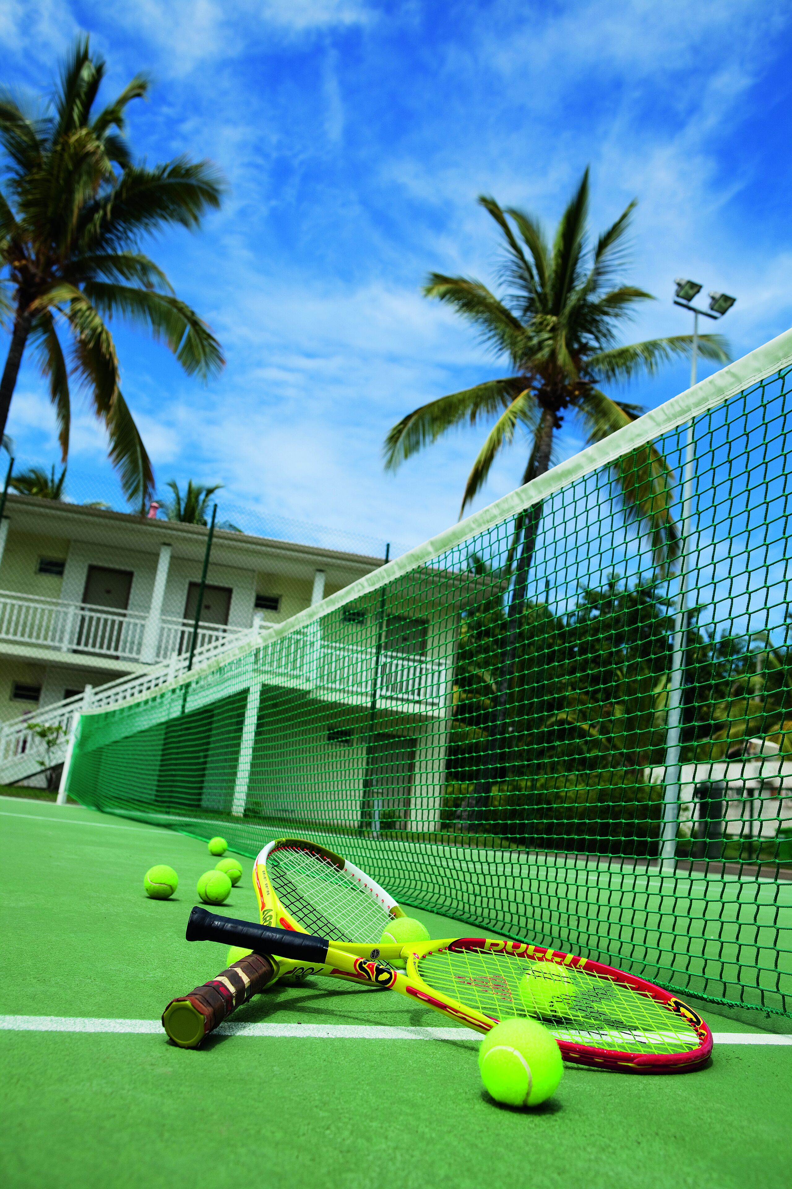 A tennis court with a net, tennis rackets, and balls.