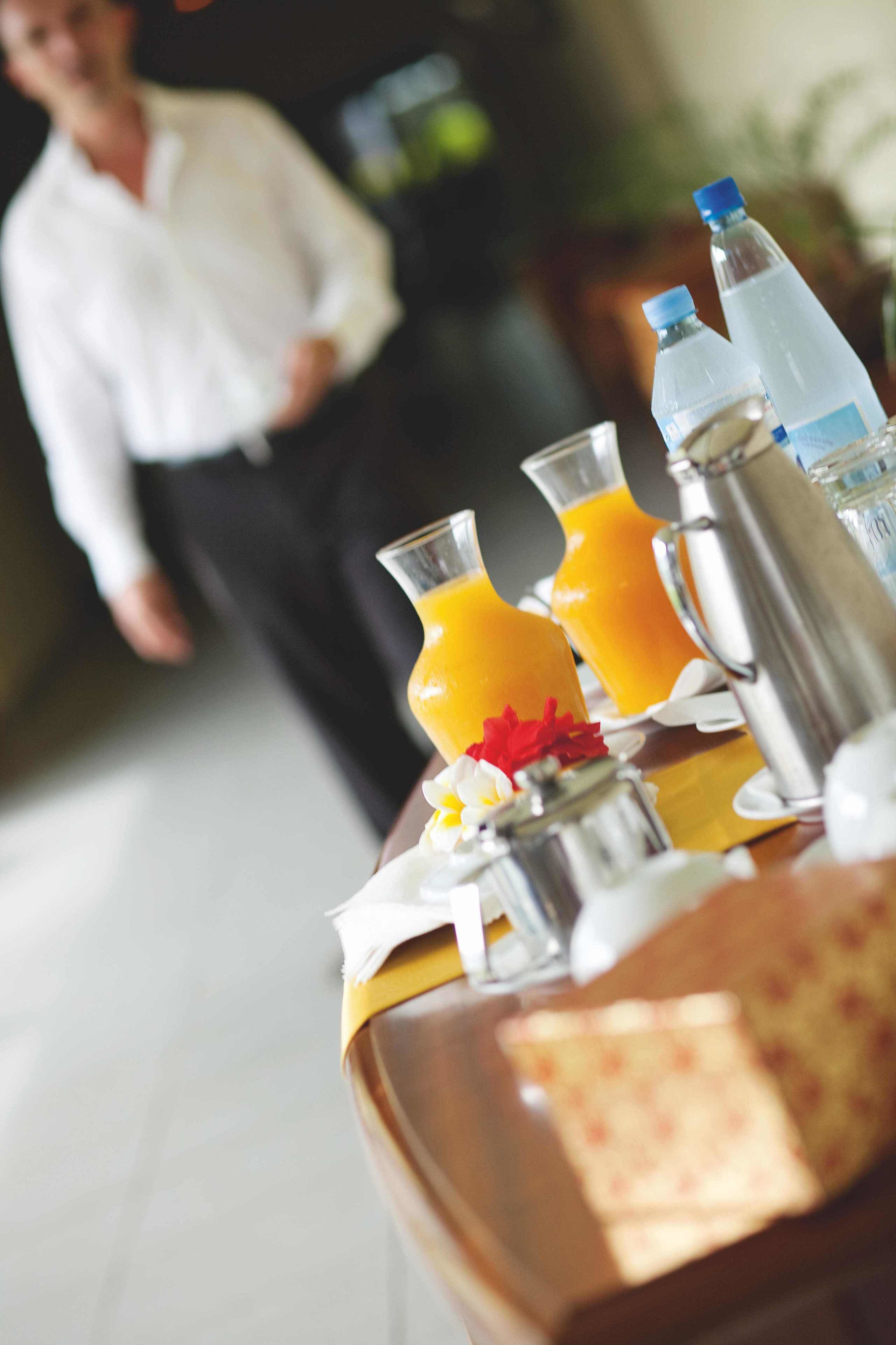 A breakfast table with orange juice, water bottles, and a coffee pot.