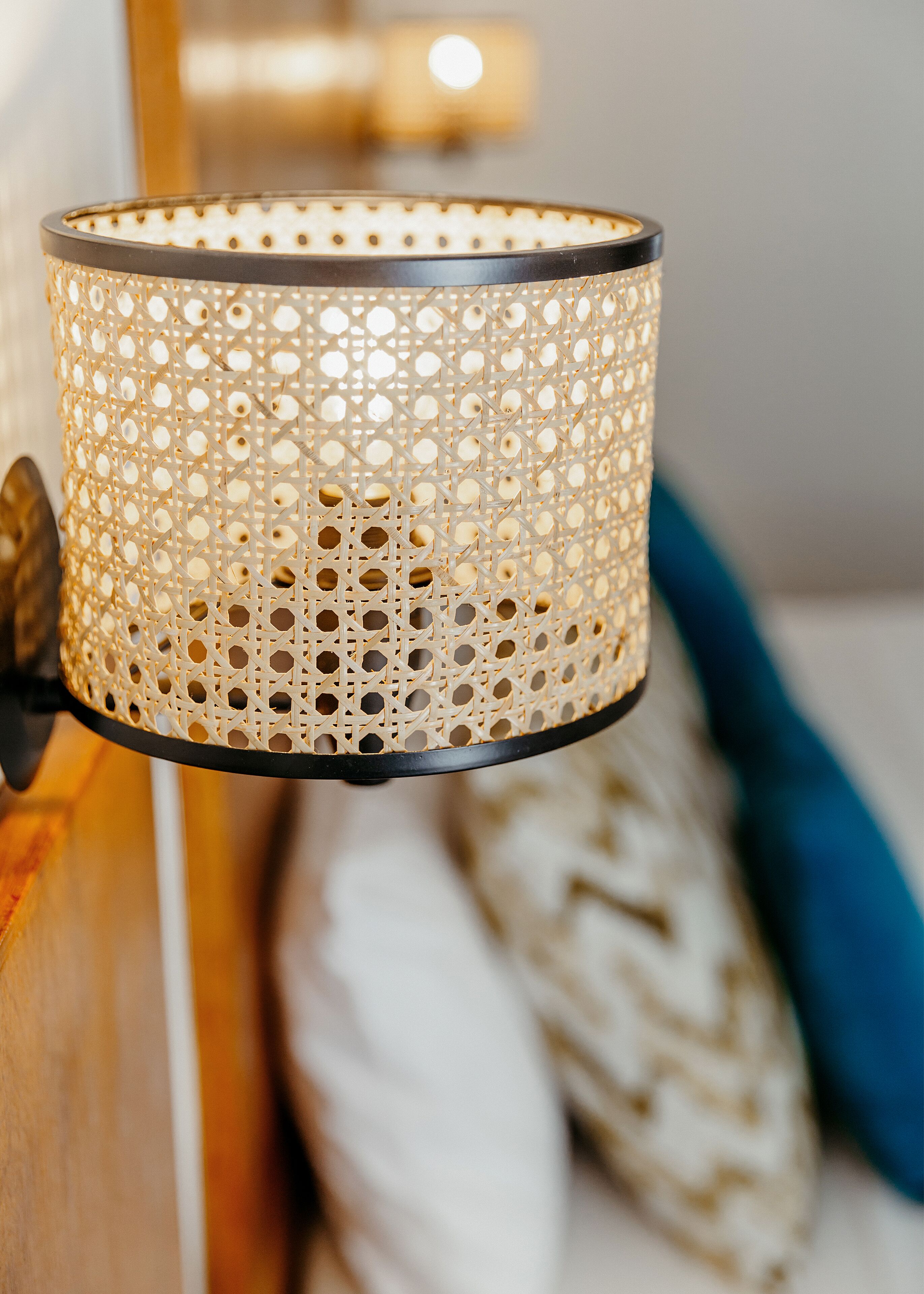 Close-up van een geperforeerde, cilindrische lamp met een zwarte rand, bevestigd aan een houten oppervlak.
