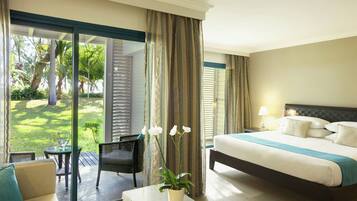 Ein Hotelzimmer mit Bett, einem kleinen Tisch, einem Stuhl und Blick auf einen Garten durch eine Schiebetür.