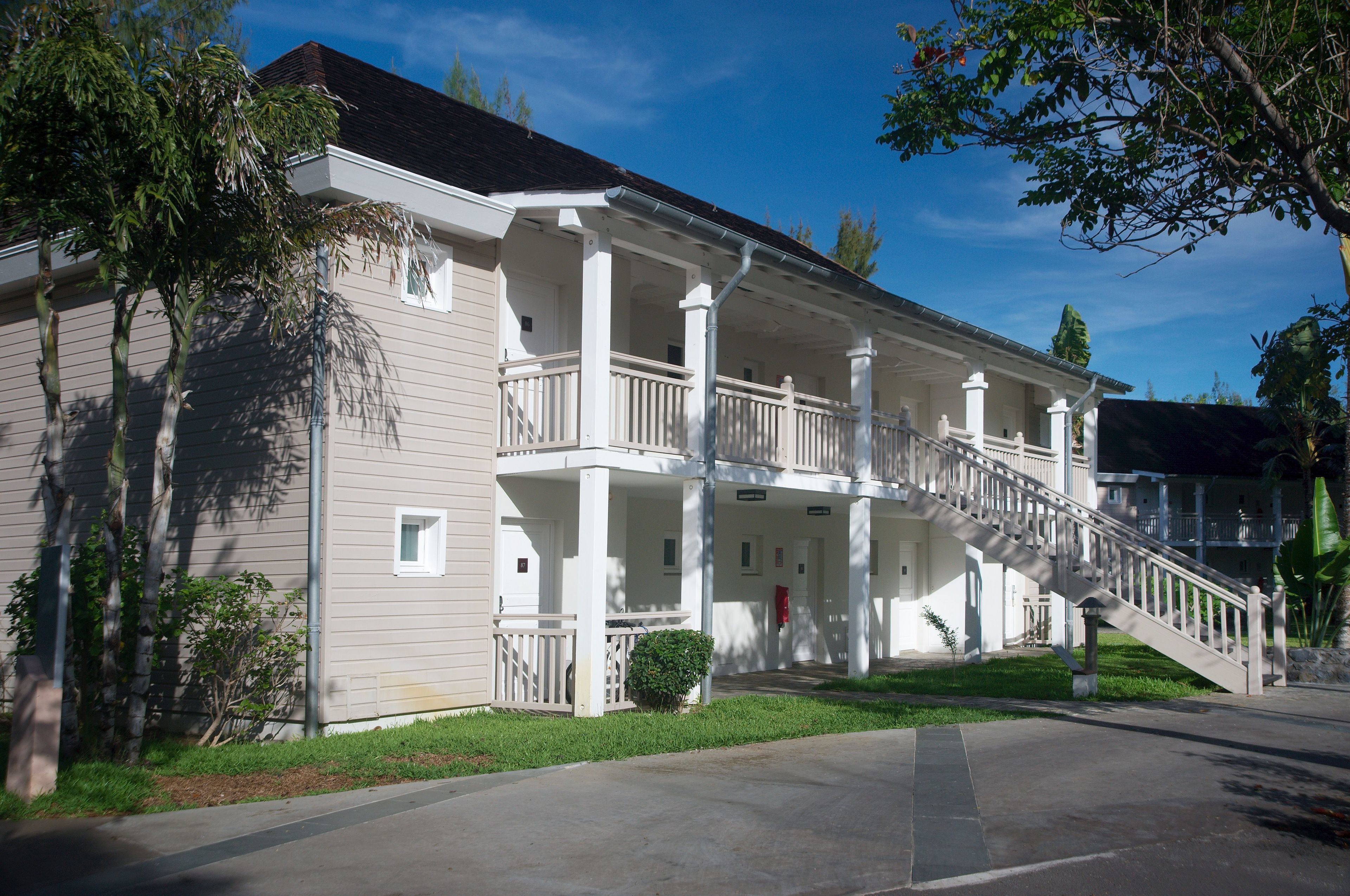 A two-story building with a covered porch and a staircase leading to the upper floor.