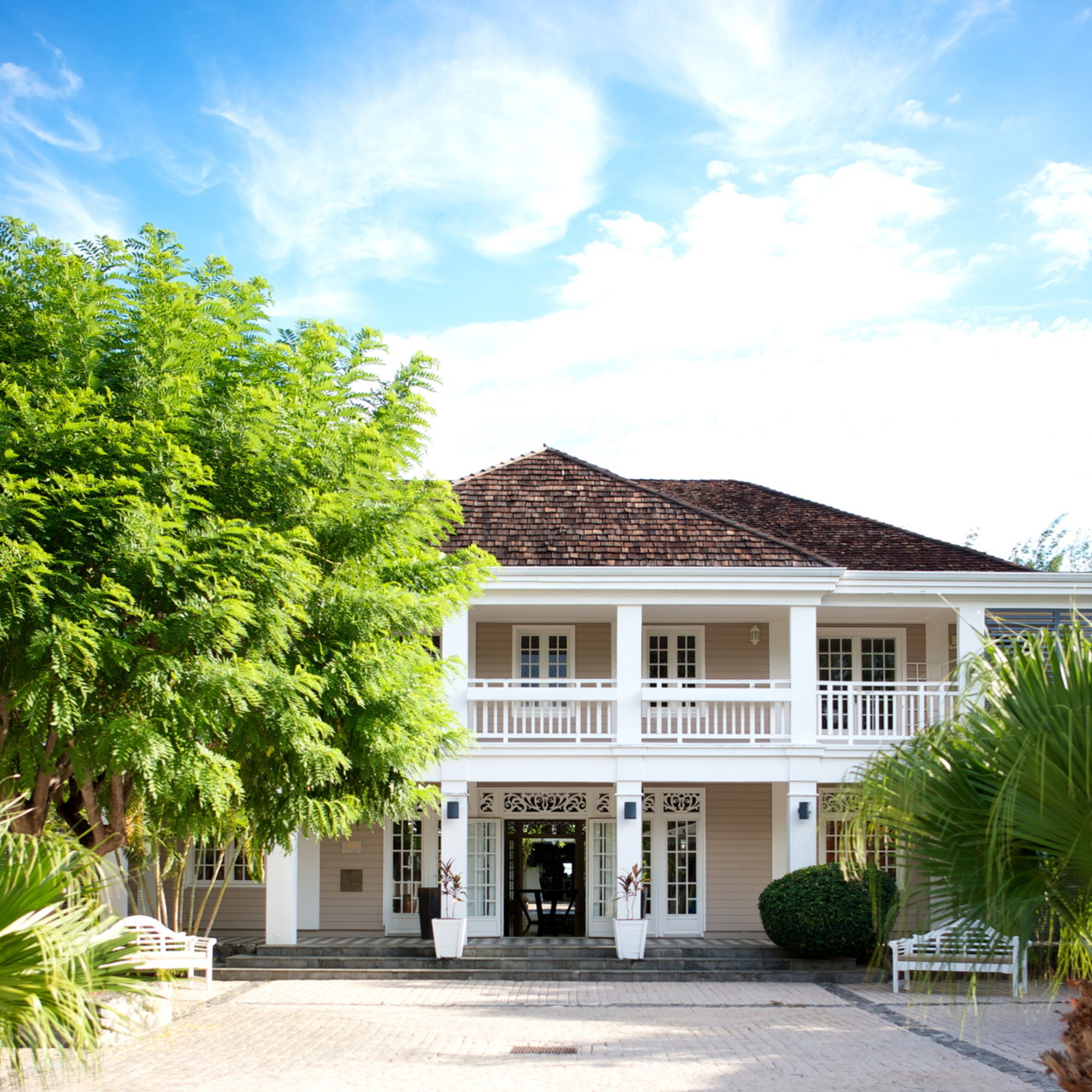 A two-story colonial-style building with a symmetrical facade, a central entrance with a decorative door, and a balcony on the upper floor.