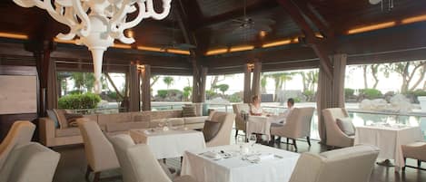 Un restaurante con terraza, vistas a la piscina y un candelabro.