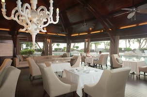 Un restaurante con terraza, vistas a la piscina y un candelabro.