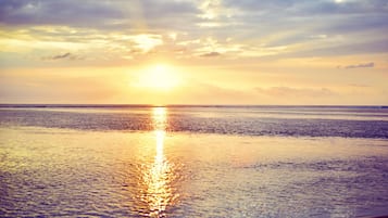 Rannalla, valkoista hiekkaa, aurinkotuoleja, aurinkovarjoja