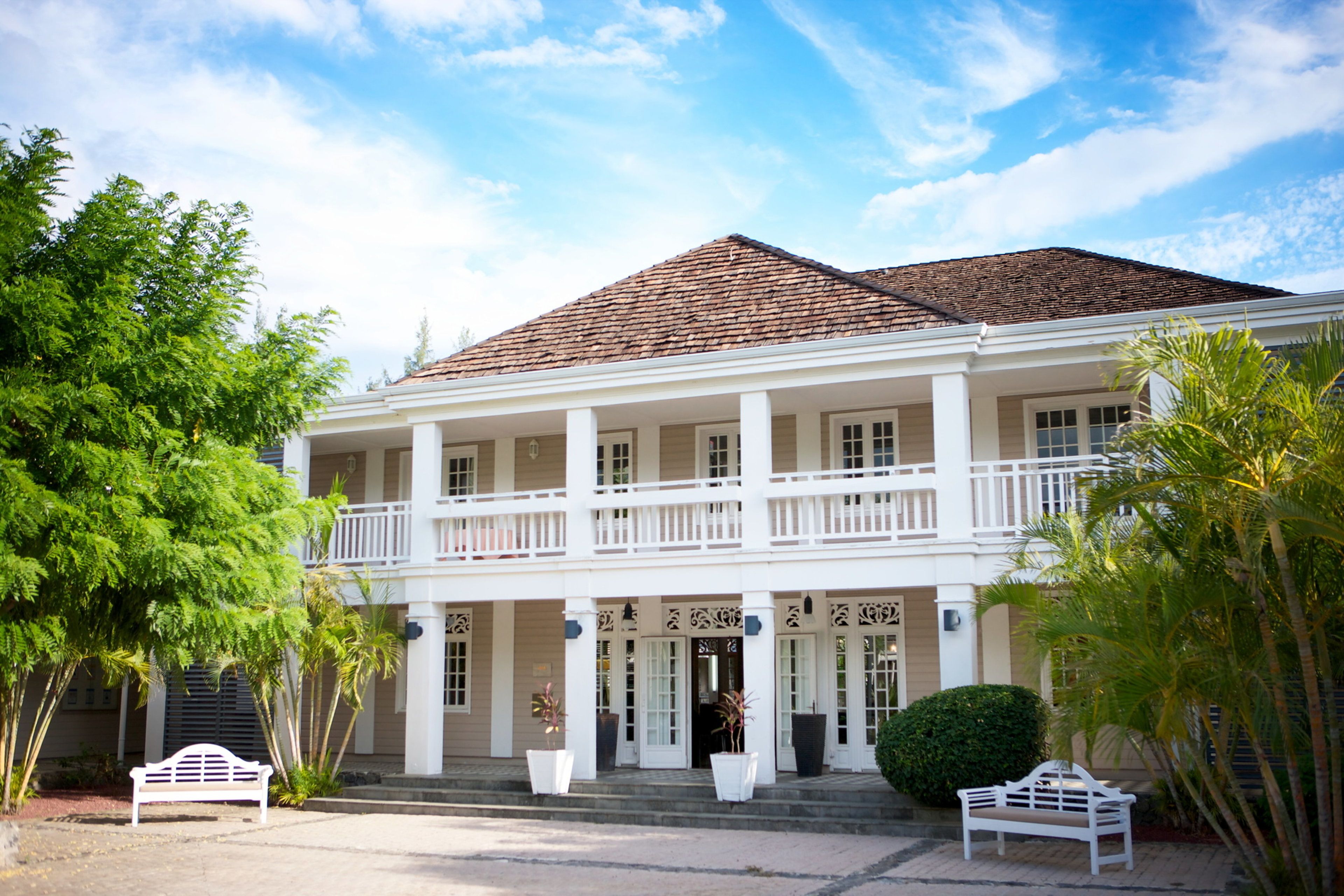 A two-story colonial-style building with a balcony, large windows, and a symmetrical facade.