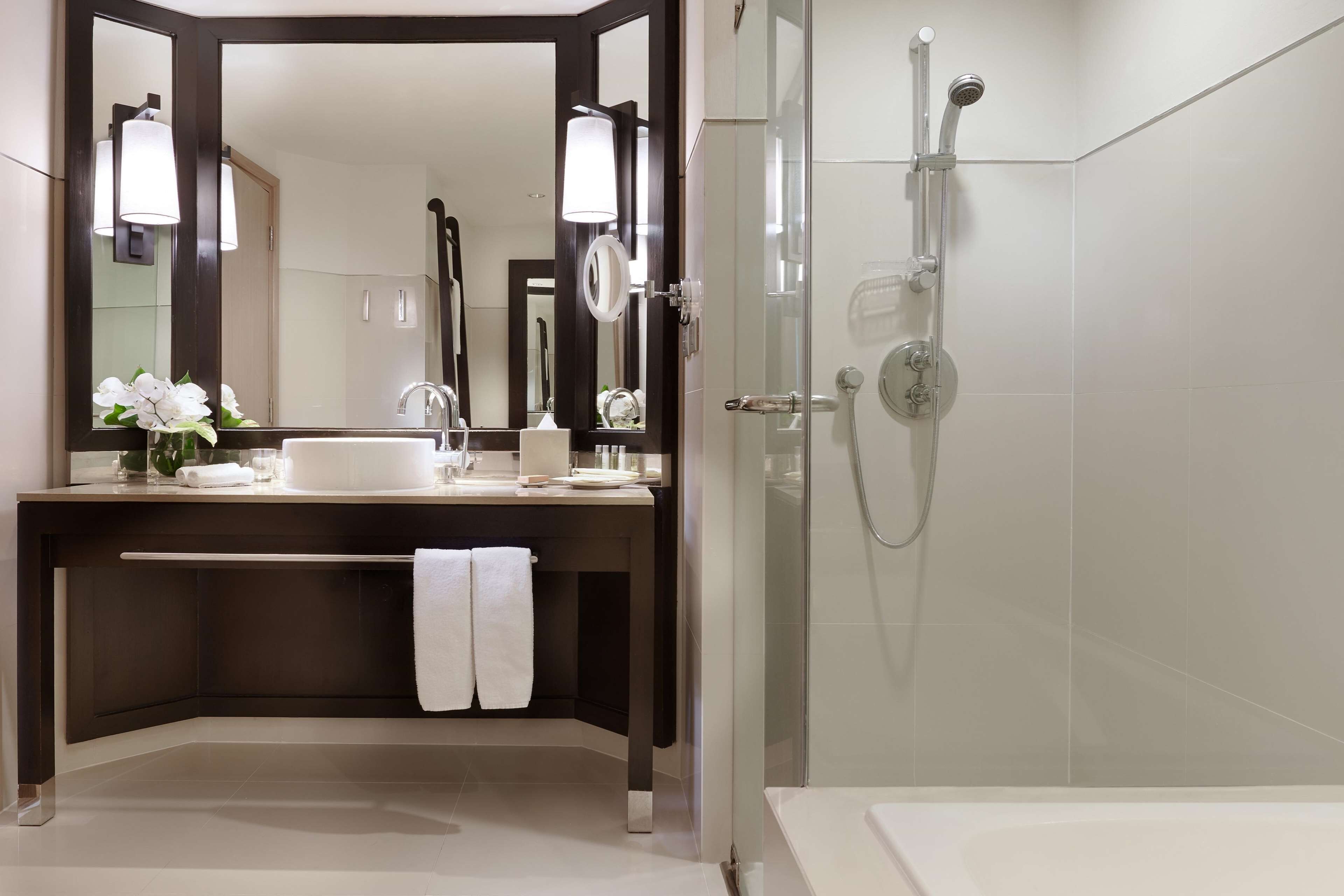 A modern bathroom with a large mirror, a sink, a shower, and a bathtub.