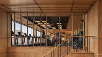 A modern interior with wooden paneling, a staircase, and exercise equipment.